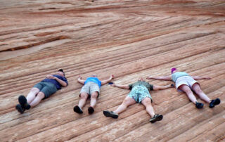 Small group of women sunning on red rocks - Canyon Calling
