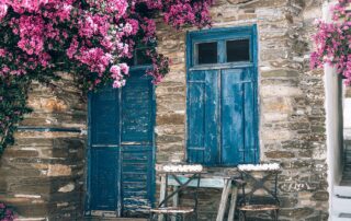 Empty cafe tables on streets of village of Tinos Island with Cycladic houses on background, Cyclades, Greece