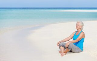 Senior Woman Meditating On Beautiful Beach