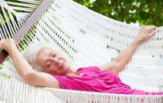 Senior Woman Relaxing In Beach Hammock