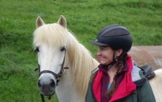 Woman smiling beside gorgeous white horse in Iceland