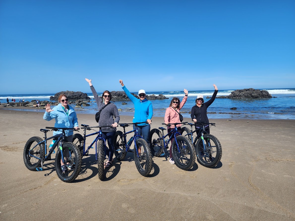 Women biking along one of Oregon's beaches - Canyon Calling Adventures