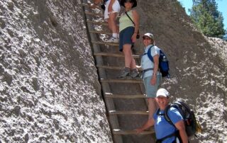 Women climbing ancient pueblo ladder in the desert mountains of NM with Canyon Calling Adventures