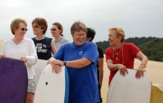 Women holding boogie boards on gal's trip in New Zealand