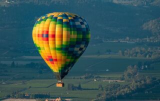 Colorful hot air balloon floating over Napa, CA - Canyon Calling Adventure Tours