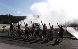Women cycling in front of geyser in Yellowstone